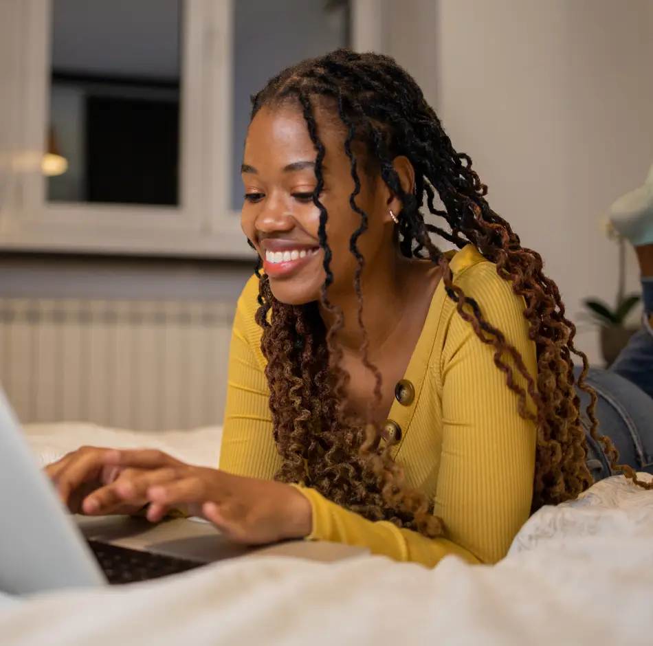 A woman studies on her laptop in bed