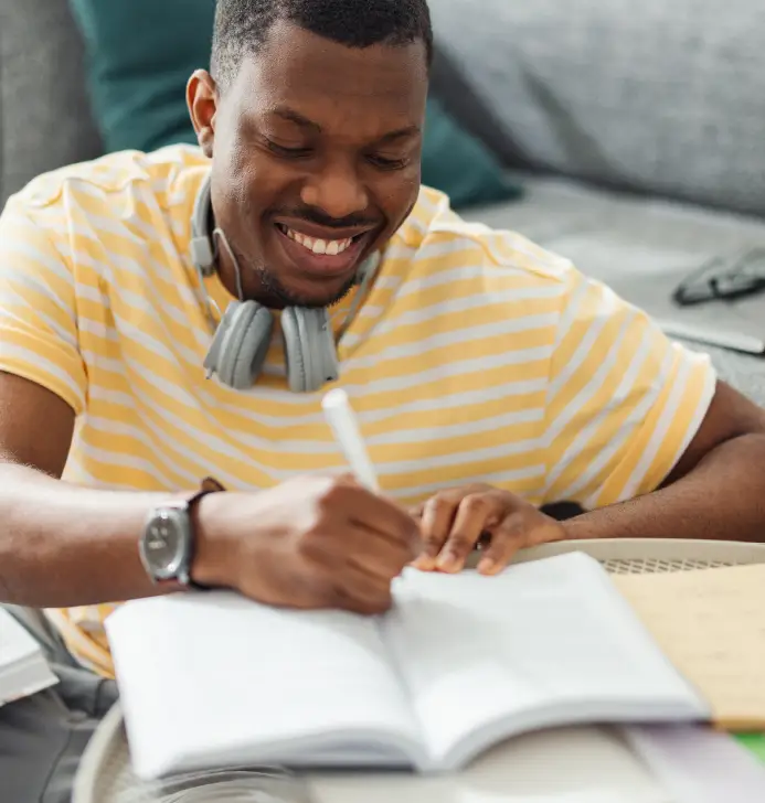 A man writes in a notebook in his living room